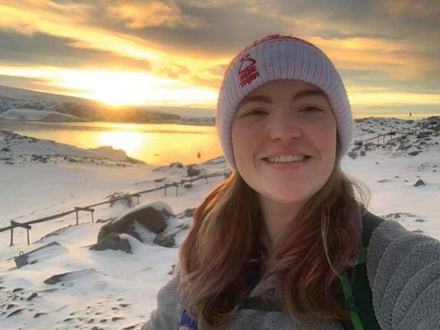 Guila Woods standing in front of a sunrise with a snowy landscape